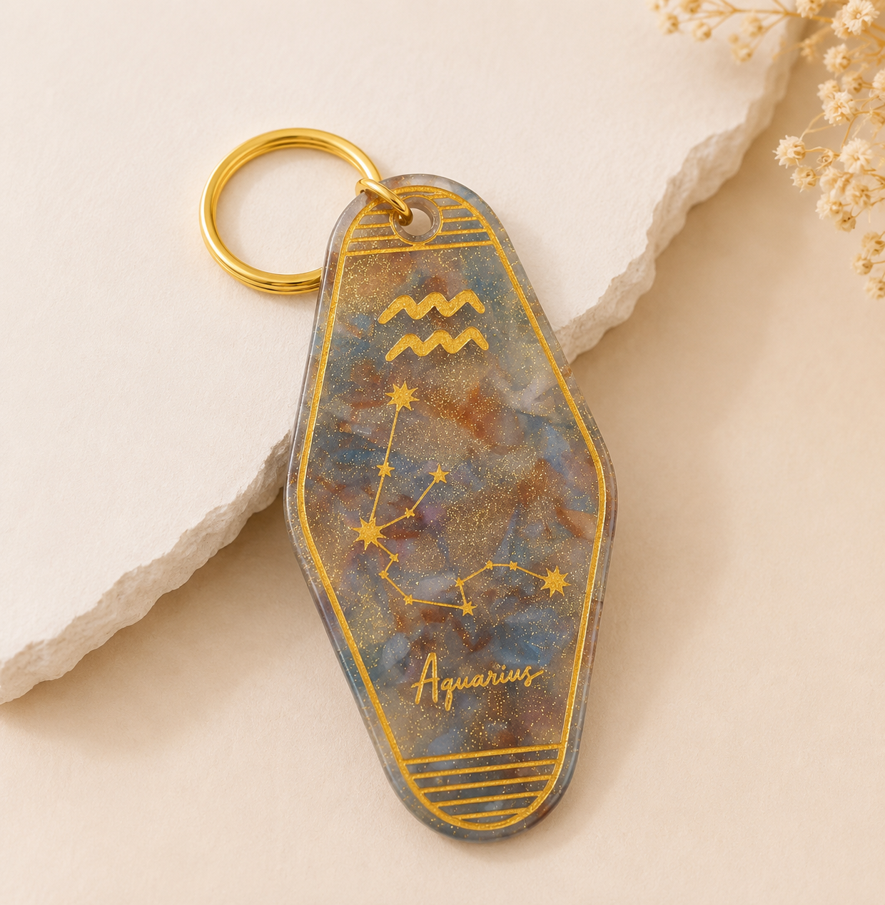 Keychain with Aquarius zodiac design on a beige background