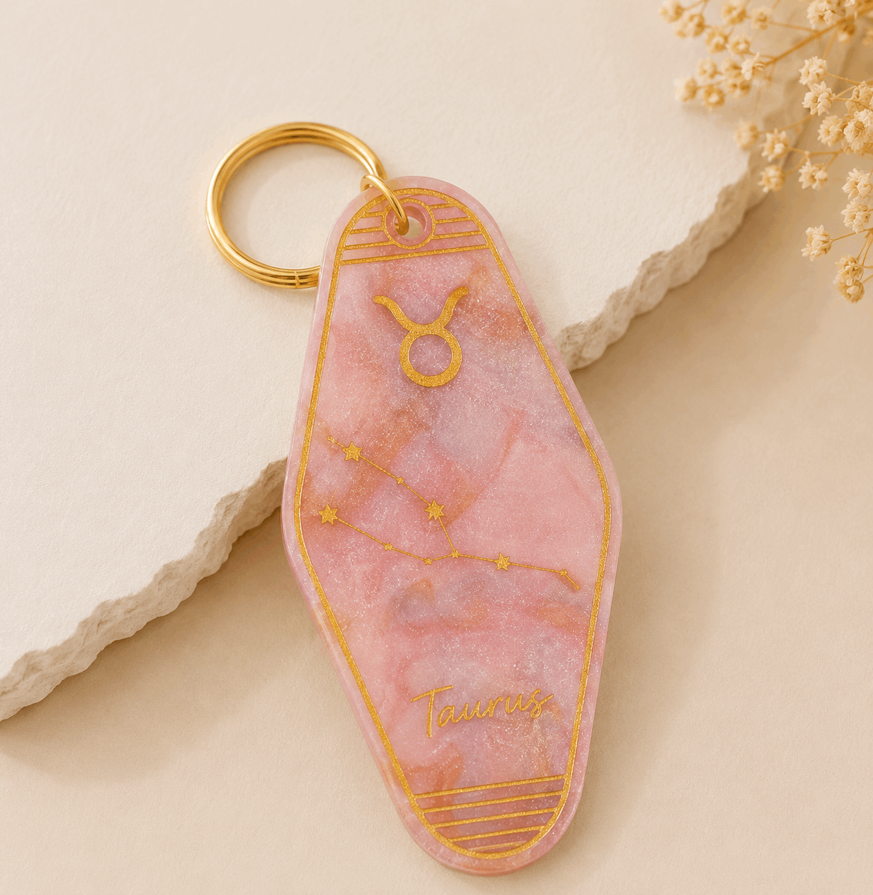Pink keychain with gold accents on a beige surface