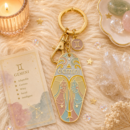 Gold 'Gemini' keychain with star sign design on a textured surface with decorative items.