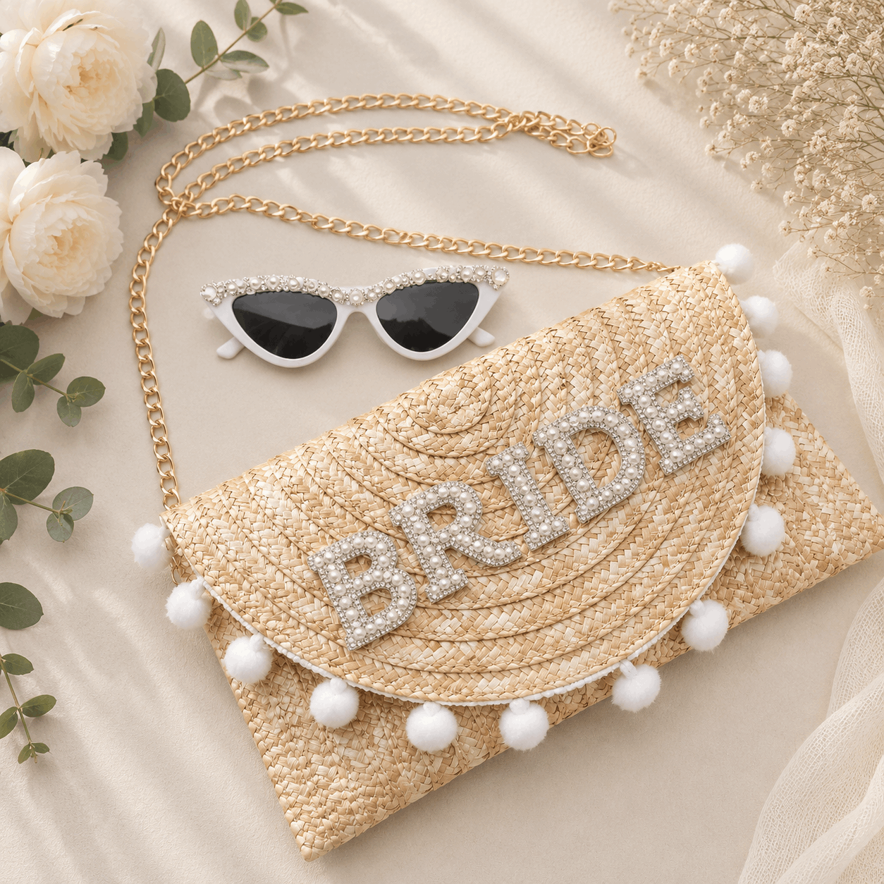 Woven clutch bag with 'BRIDE' embellishments and sunglasses on a light background