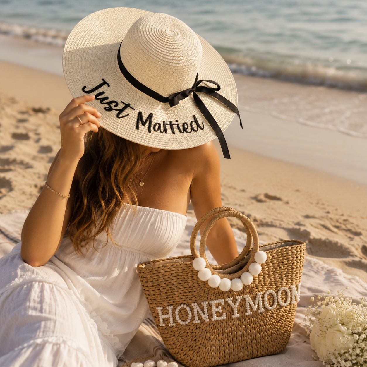 Woman on a beach wearing a 'Just Married' hat and holding a 'Honeymoon' bag.