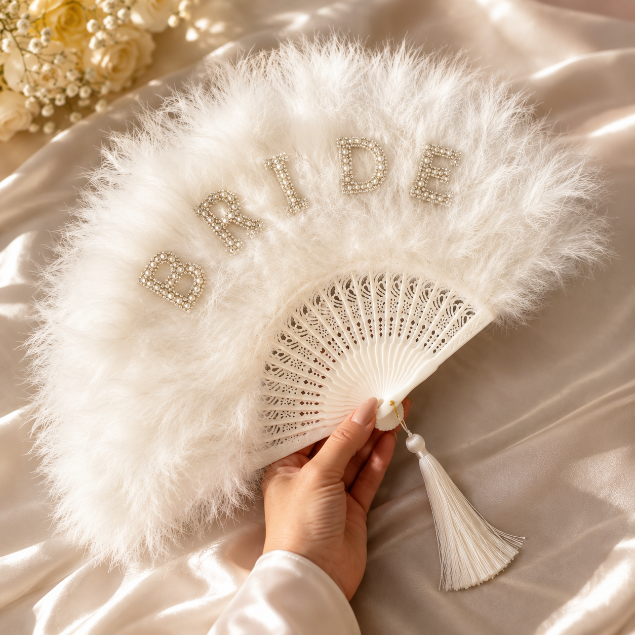 White feathered fan with 'BRIDE' letters held by a hand on a soft beige background