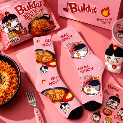 Pink socks with cartoon character design on a pink background, featuring the brand 'Buldak'.