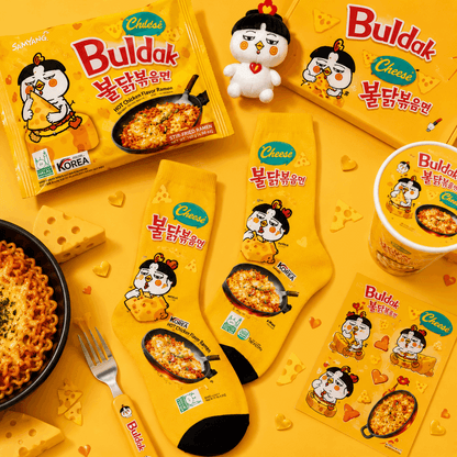 Buldak Cheese Hot Chicken Noodle packaging and products on a yellow background