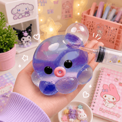 Hand holding a cute, colorful slime toy with a background of stationery and decor items.
