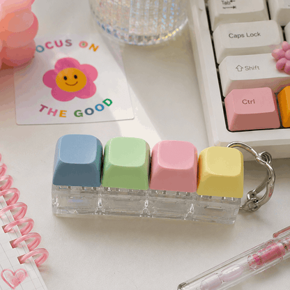 Colorful key-shaped erasers on a desk with a keyboard and stationery items.