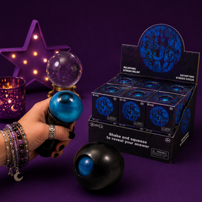 Hand holding a blue stress ball with a box of similar balls in the background on a purple surface.