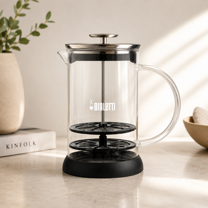 Clear glass French press with black base and handle on a light surface, featuring Bialetti logo.