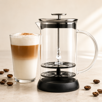 French press coffee maker with a glass of latte and scattered coffee beans on a light background