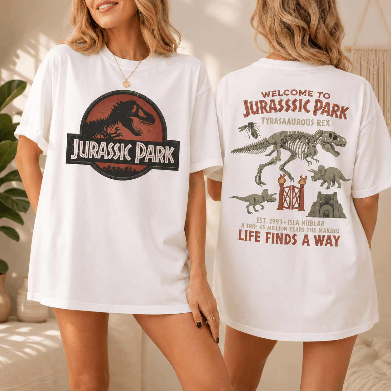 Two women modeling matching oversized white T-shirts with Jurassic Park graphics, showing both the front and back designs in a softly lit indoor setting.