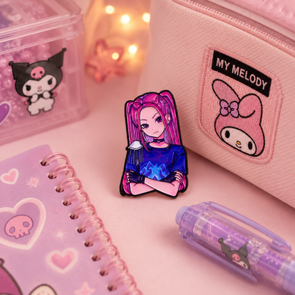 A pink and purple enamel pin featuring an anime character with pink hair, styled on a pink desk alongside a pink pencil case, notebook, and pen.