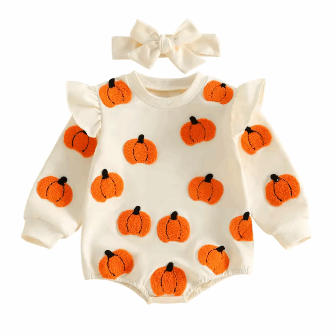 A baby long-sleeve romper in cream with orange pumpkin prints, shown with a matching cream bow headband on a white background.