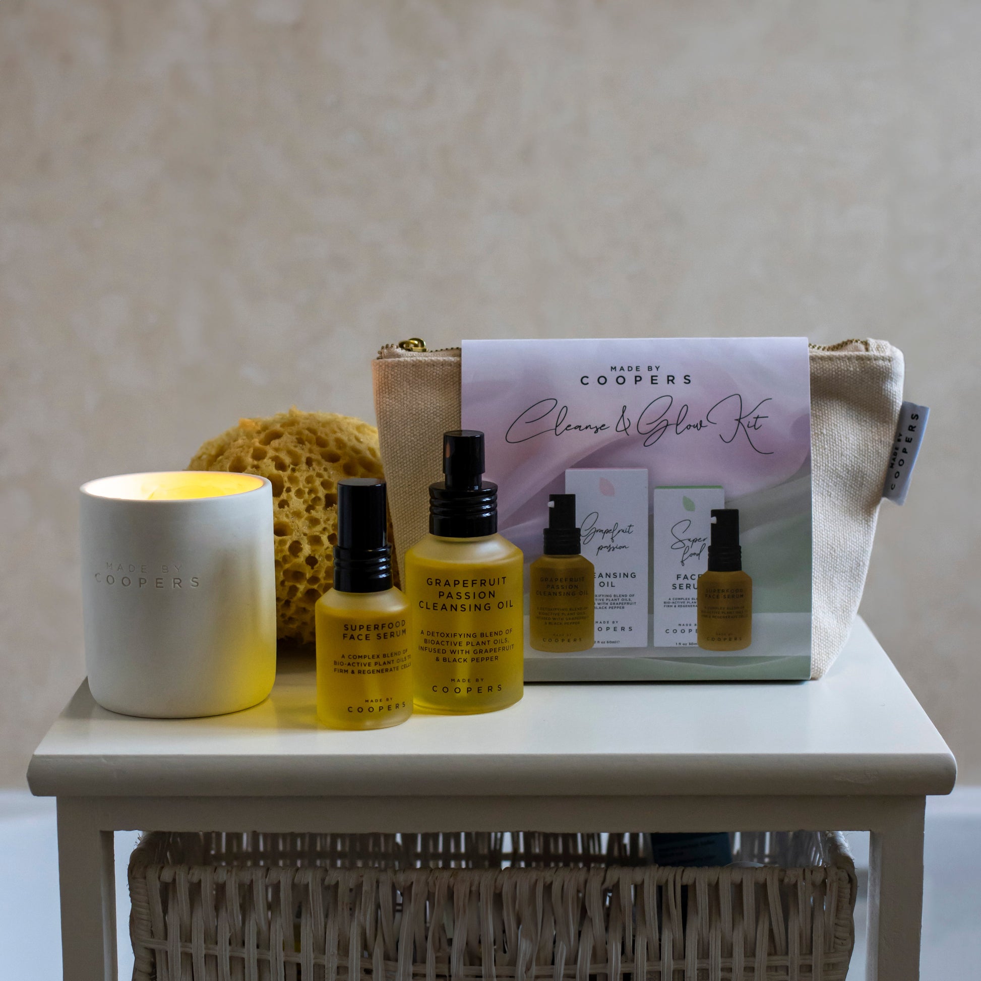 Cooper's skincare products including bottles, a candle, and a box on a table.