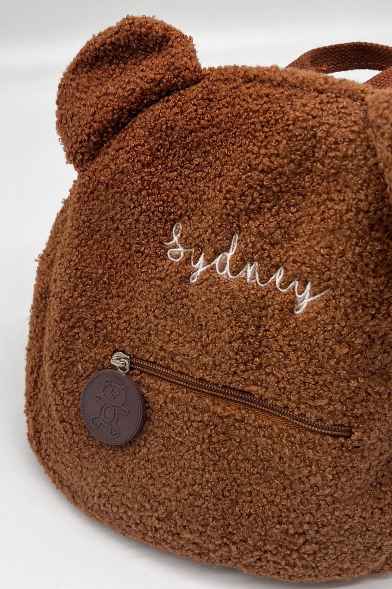 Brown teddy bear-shaped bag with 'Sydney' embroidery on a white background