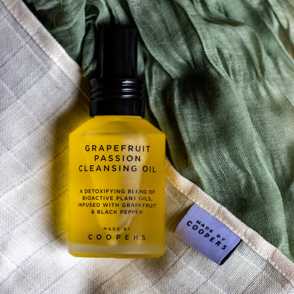 Yellow bottle of grapefruit passion cleansing oil with a Coopers label on a textured fabric background