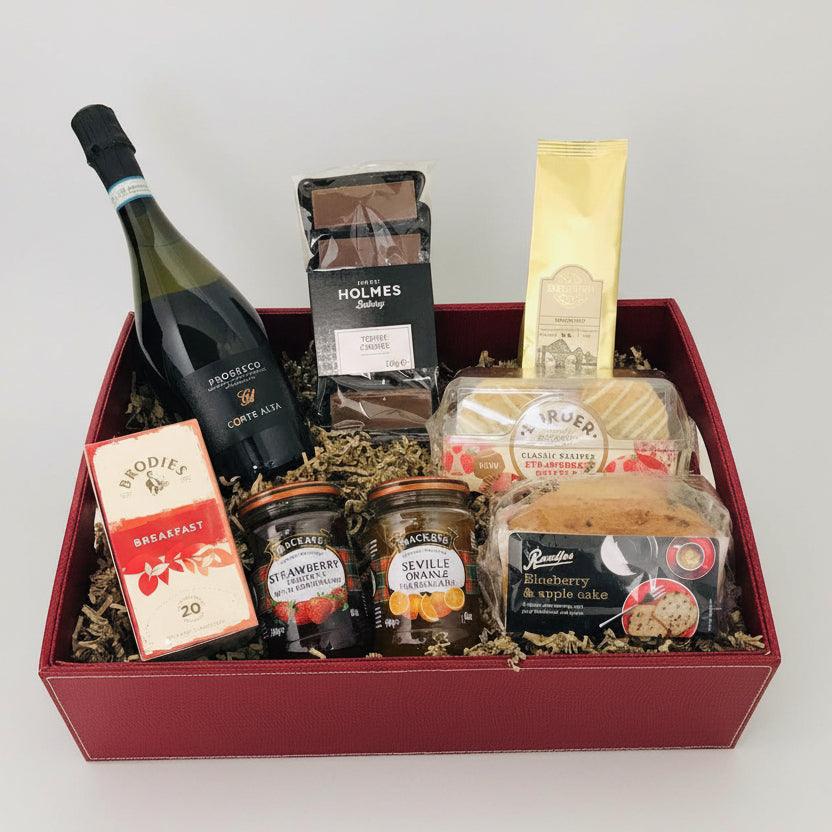 Gift basket with wine, jams, and other snacks in a red box.