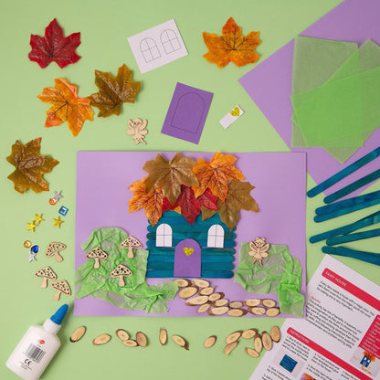 Children's craft kit with paper house, leaves, and craft supplies on a green background