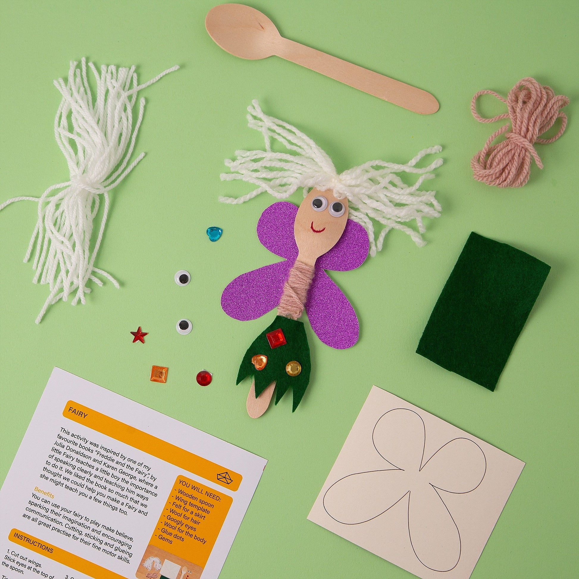 Craft kit with fairy decoration, materials, and instructions on a green background