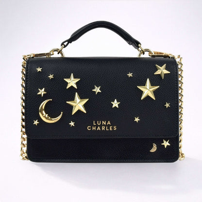 Black handbag with gold stars and moon design on a white background