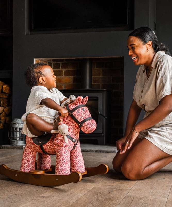 Woman and child playing with a rocking horse in a cozy room.