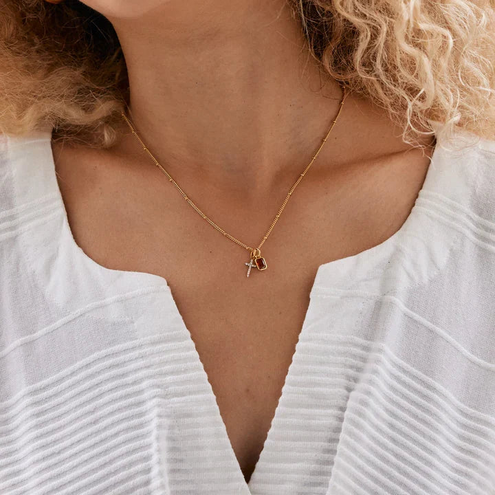 Woman with curly hair wearing a white top outdoors