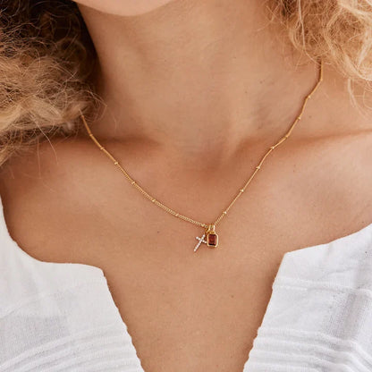 Gold necklace with a cross pendant on a person wearing a white top