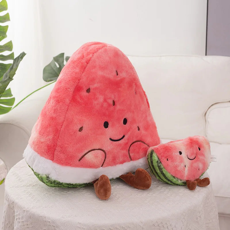 A cute plush watermelon toy with a large triangular watermelon slice and a smaller slice companion, both with embroidered smiling faces and brown feet, sitting on a white tablecloth.