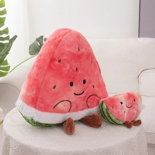 A cute plush watermelon toy with a large triangular watermelon slice and a smaller slice companion, both with embroidered smiling faces and brown feet, sitting on a white tablecloth.