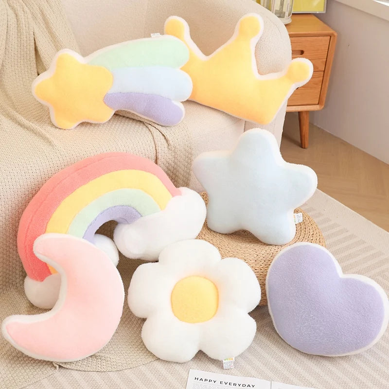 Set of colorful plush toys shaped like a rainbow, star, moon, and flower on a beige couch.