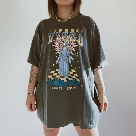 Person wearing a graphic t-shirt with a celestial design and text on a plain background