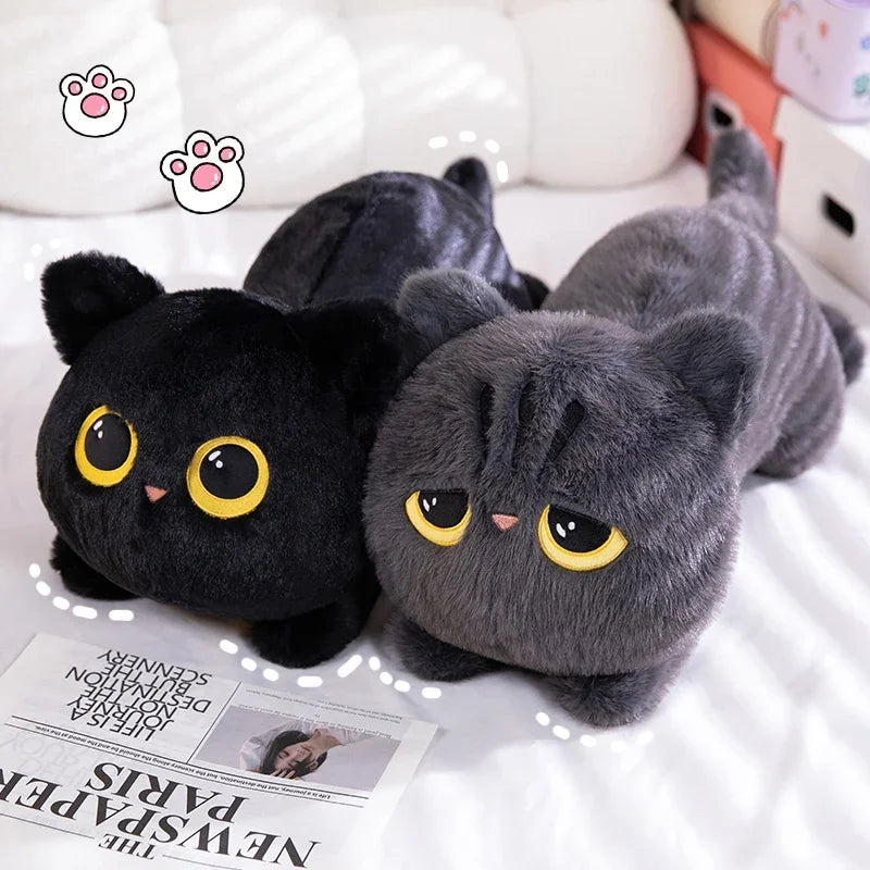 Two plush cat toys, one black and one gray, on a surface with a newspaper underneath.