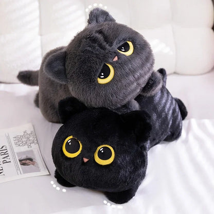 Two plush cat toys, one gray and one black, on a white surface with a magazine underneath.