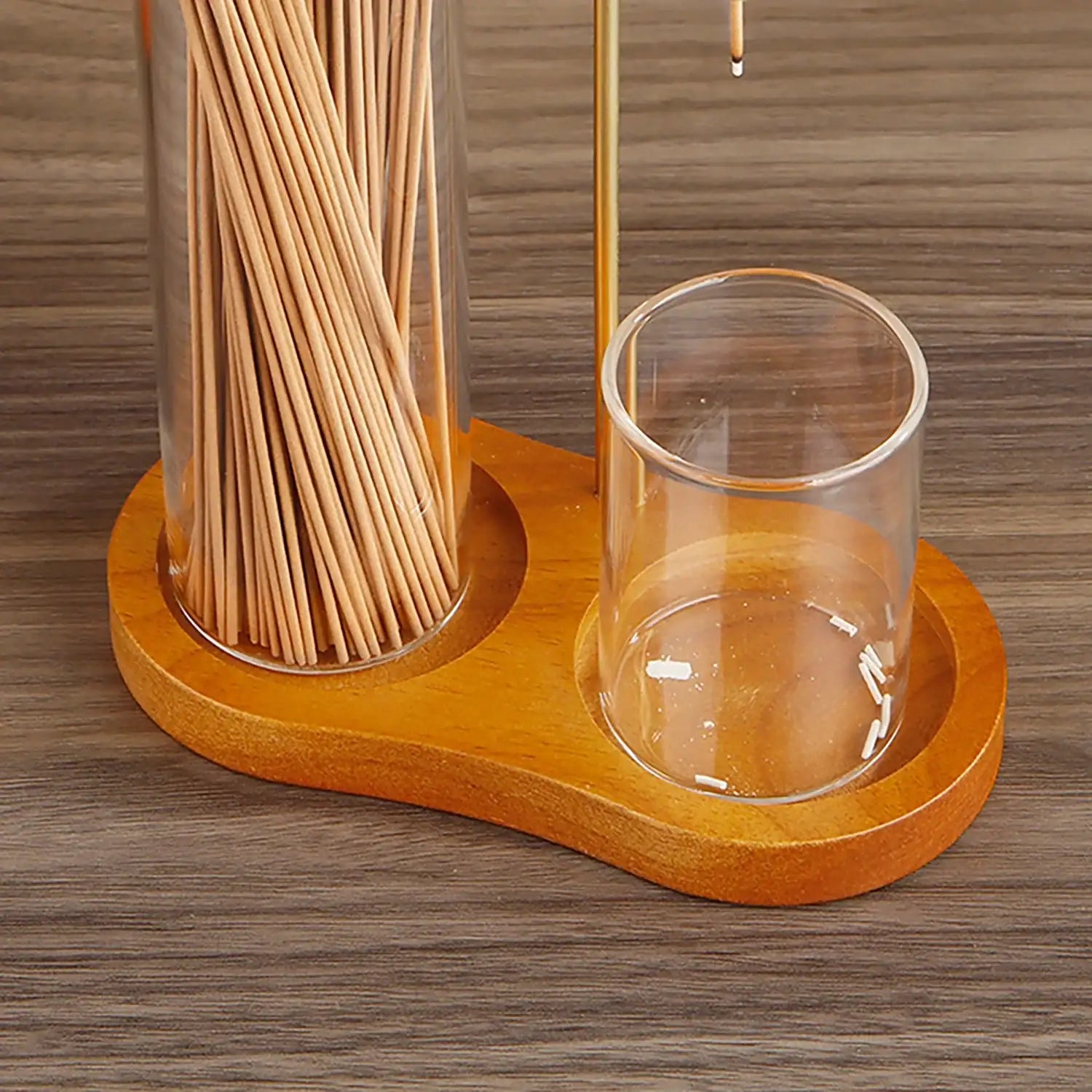 Wooden holder with glass and jar of wooden sticks on a wooden surface
