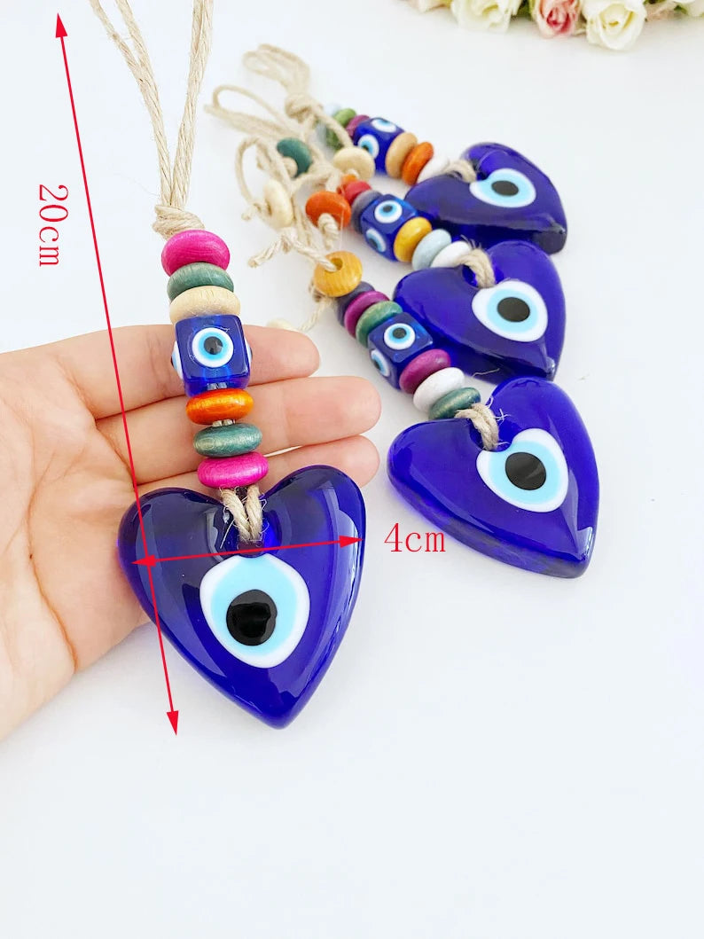 Heart-shaped evil eye charms with colorful beads, held by a hand for scale.