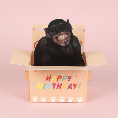 Monkey inside a 'Happy Birthday!' box with colorful text and paw prints on a white background
