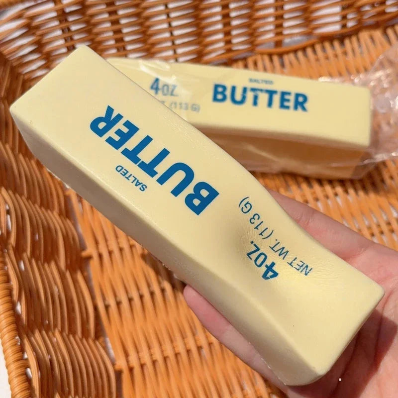Bar of butter held by a hand with a woven basket in the background