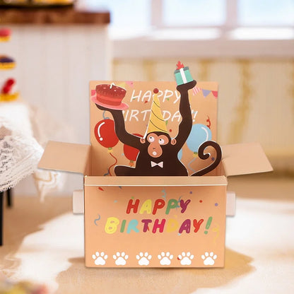 Cartoon monkey in a birthday box with 'Happy Birthday!' text on a blurred background