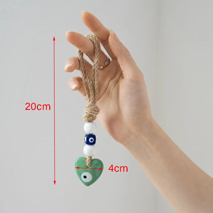 Hand holding a decorative heart charm with measurement details on a plain background