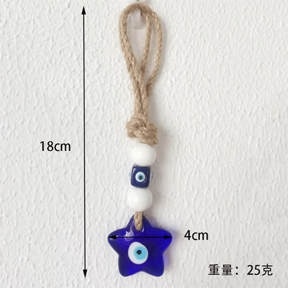 Star-shaped blue evil eye charm with a white bead on a rope against a white background