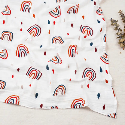 White blanket with colorful rainbow pattern on a light wooden surface