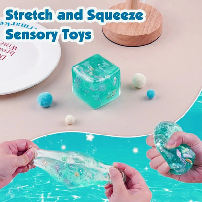 Sensory toys including a blue cube and clear gel-like toy with hands stretching and squeezing them on a light background.
