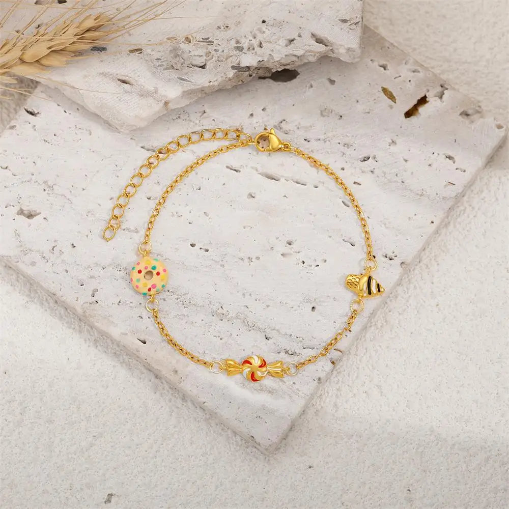 Gold bracelet with colorful charms on a stone surface