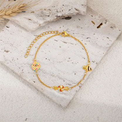 Gold bracelet with colorful charms on a stone surface