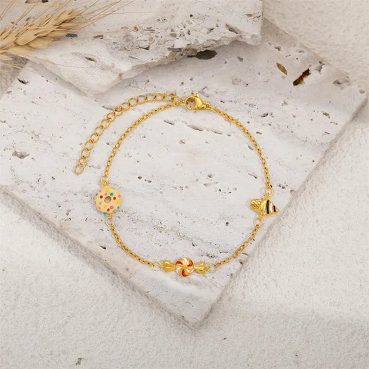 Gold bracelet with colorful charms on a stone surface