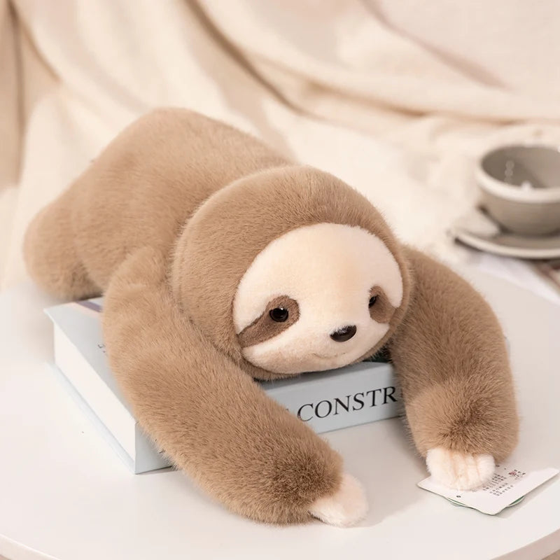 Plush sloth toy on a book with a blurred background