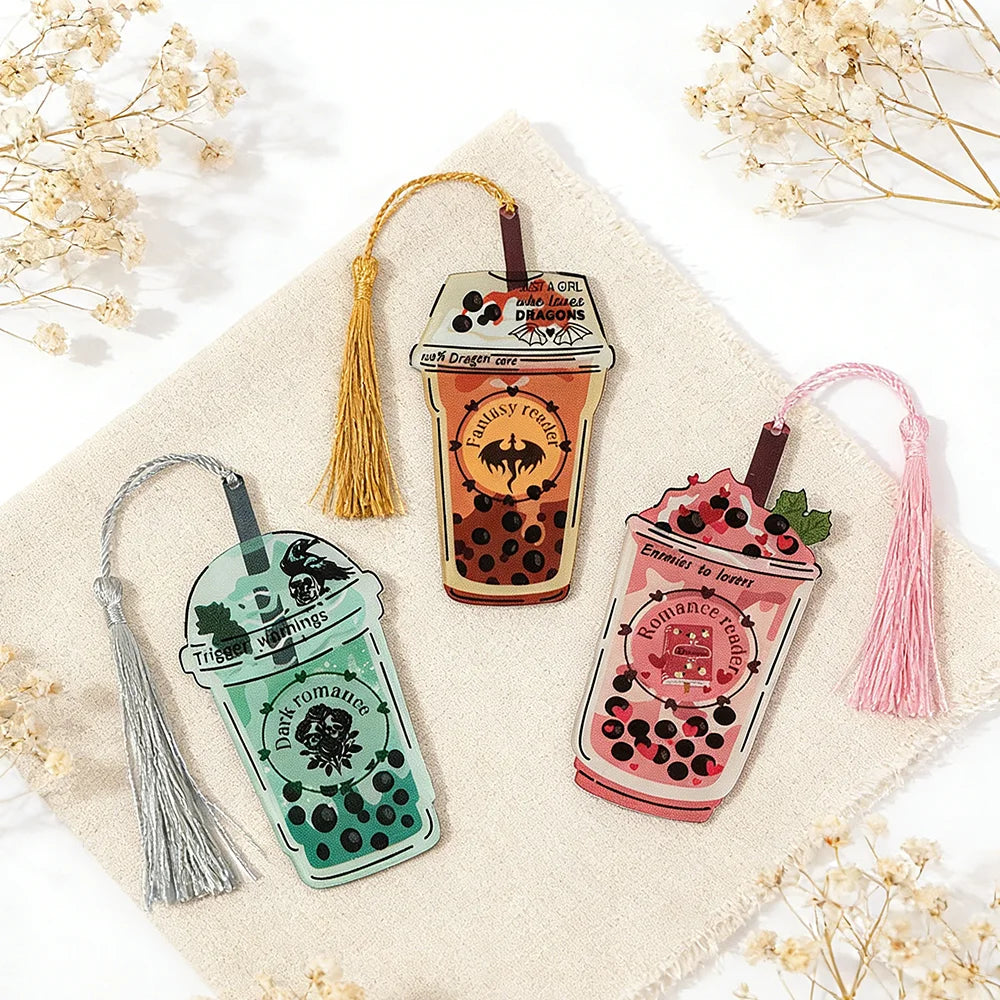 Three decorative bookmarks shaped like bubble tea cups with tassels on a textured surface.