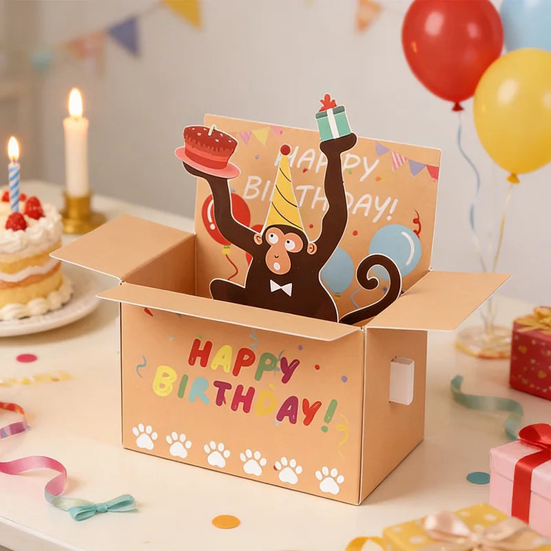 Birthday card with monkey design in a box, surrounded by balloons and cake.