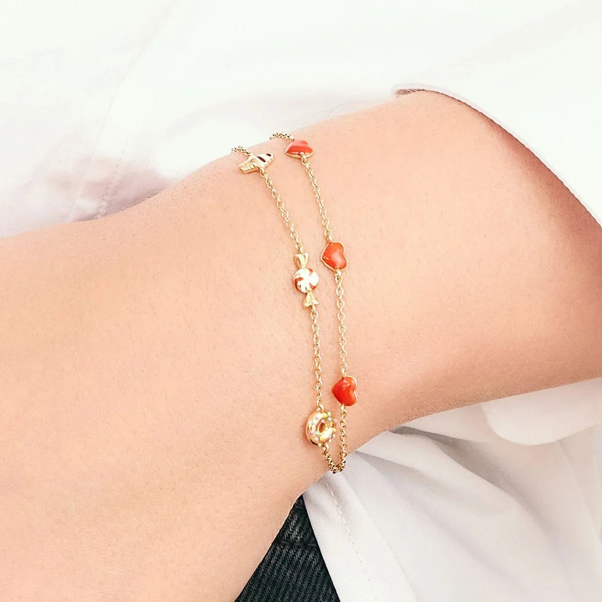 Gold bracelet with red beads on a wrist against a white background