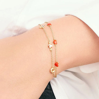Gold bracelet with red beads on a wrist against a white background