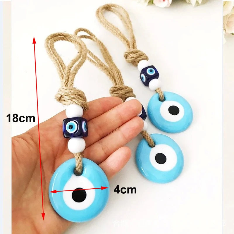 Blue evil eye charms with measurement details held by a hand.